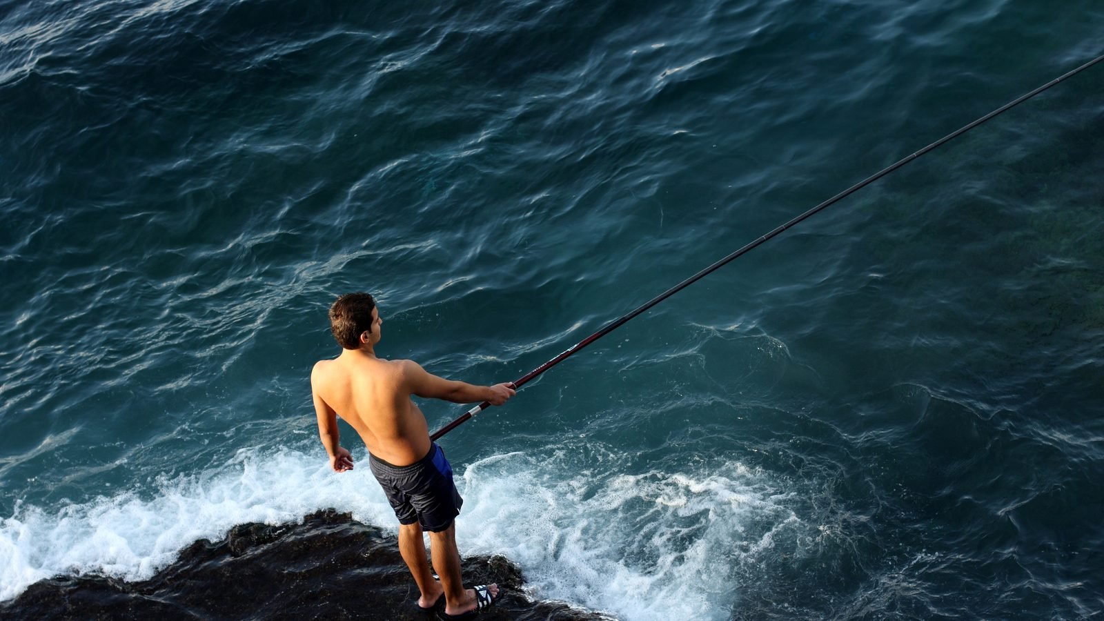 A man fishing from the rocks along the Beirut Corniche